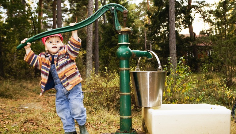 Pojke som pumpar vatten