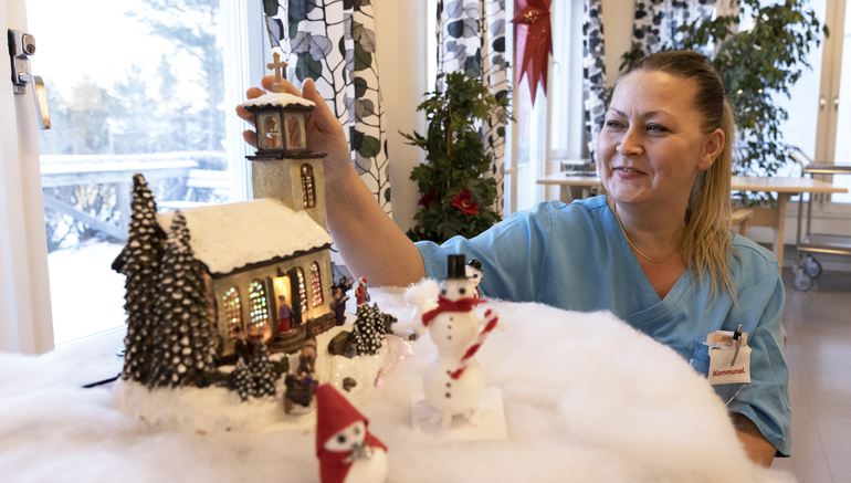 Kvinna i vårdkläder dekorerar julpynt