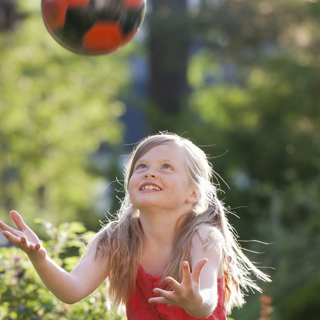 Flicka leker med en boll