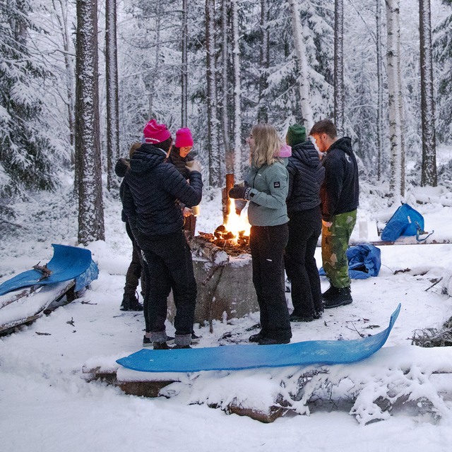 Grupp ungdomar runt en lägereld i vintermiljö