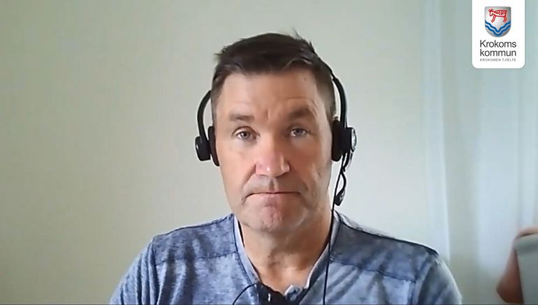 Bild från ett videomöte med en man som har hörlurar på huvudet.