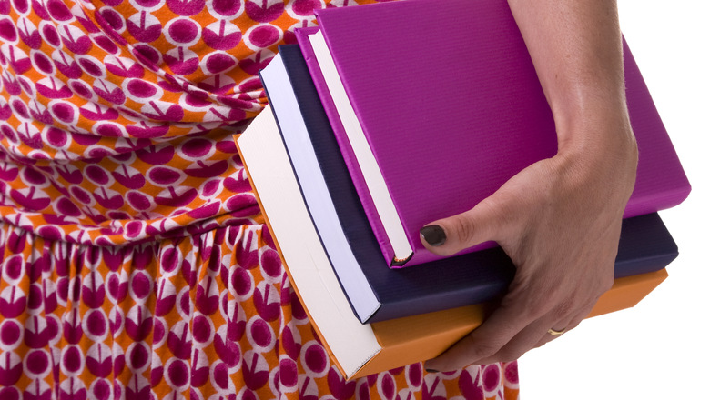 detail of a teenager carrying a stack of school books