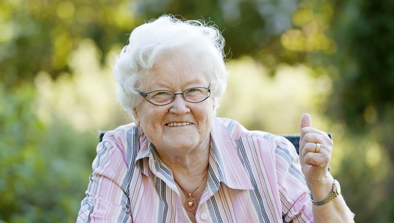 Bild på leende äldre kvinna som gör tummen upp