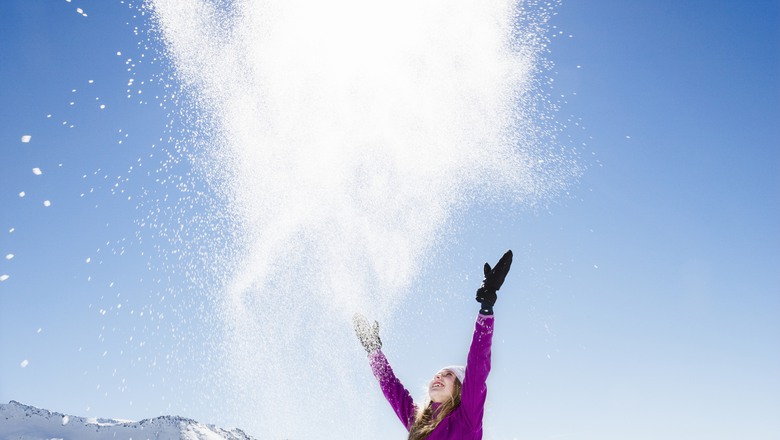 Flicka kastar snö i luften